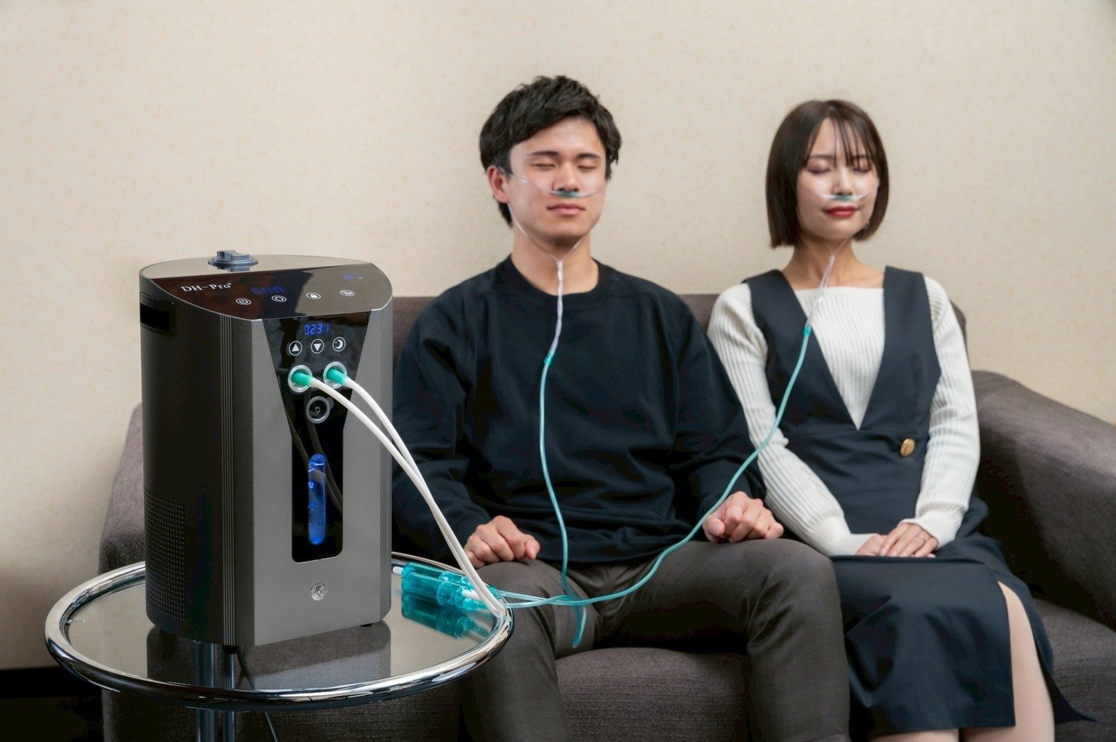 ソファに並んで座り、1台のDH-Proから一緒に水素を吸う男女