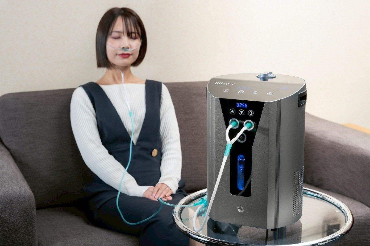 ソファに座り、横に置いたDH-Proから水素を吸う女性