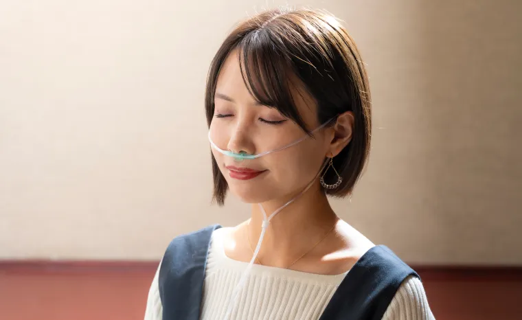 鼻に吸入チューブをつけた女性