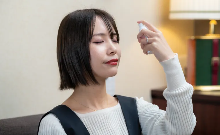 ミストボトルで水素水を顔に散布する女性